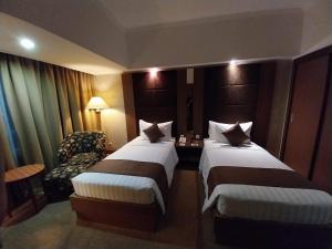 ein Hotelzimmer mit 2 Betten und einem Stuhl in der Unterkunft Horison Ultima Menteng Jakarta in Jakarta