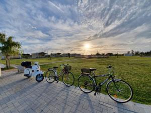 drei Fahrräder, die neben einem Roller in einem Park geparkt sind in der Unterkunft Vento etrusco in Riotorto