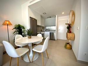 una sala da pranzo con tavolo bianco e sedie bianche di MyChoice Frida by Bossh! Apartments a Rota