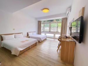 a hotel room with two beds and a television at Travel Life 源旅生活民宿 in Shuili