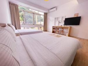 a hotel room with two beds and a television at Travel Life 源旅生活民宿 in Shuili