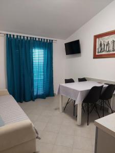 a room with a table and chairs and a blue curtain at Apartment Roglić in Rab