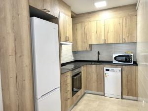 cocina con armarios de madera y nevera blanca en Apartament comfortable amb vistes i cèntric by RURAL D'ÀNEU, en Esterri d'Àneu