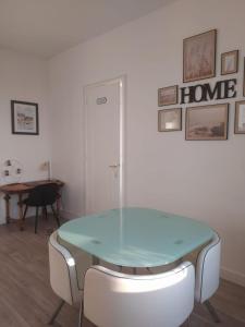 een glazen tafel en witte stoelen in een kamer bij Le Rayon Vert vue mer in Fécamp