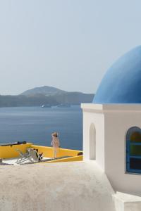 a person standing on the side of a building looking at the water at Ilivatos in Oia