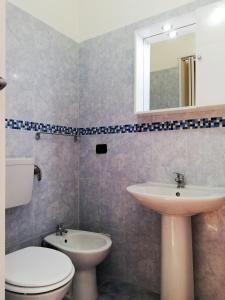 een badkamer met een wastafel, een toilet en een spiegel bij Via Pisa in Riposto