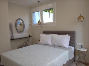 a bedroom with a bed with white sheets and a mirror at Oasis Apartments in Áyios Andréas