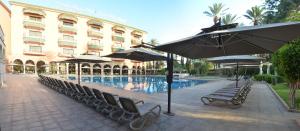 einen Pool mit Stühlen und Sonnenschirmen neben einem Gebäude in der Unterkunft Royal Mirage Deluxe in Marrakesch