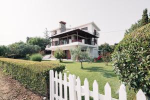 a white picket fence in front of a house at Theoni’s country house with garden and sea view in Alexandroupoli