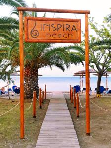 een bord voor een strand met een houten loopbrug bij Inspira Boutique Hotel Thassos - Adults Only in Prinos