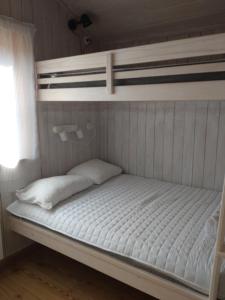 a bunk bed with two white pillows on it at Fyrklöverns Stugby in Rättvik