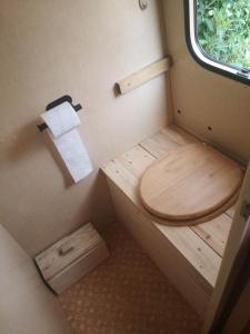 a toilet with a wooden seat in a small room at Caravane Vintage Esparadenn l'esprit d'antan in Guengat