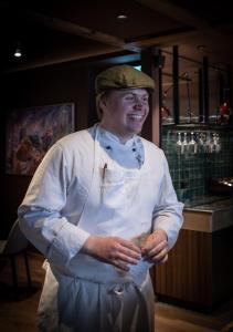 Ein Mann in einem Köchen-Outfit steht in einem Restaurant in der Unterkunft Bergstadens Hotel og SPA in Røros