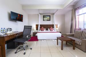 Cette chambre comprend un lit, un bureau et un canapé. dans l'établissement Mashpark Apartments, à Nairobi