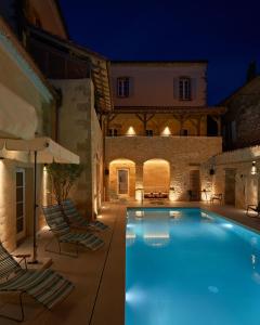 a swimming pool in a villa at night at Hotel Le Chevalier Bleu in Monpazier