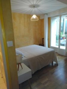 a bedroom with a white bed and a large window at Spacieuse maison de village climatisée avec jardin patio in Bessan
