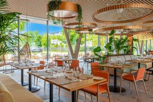 un ristorante con tavoli, sedie e ampie finestre di REED Luxury Hotel by Balaton a Siófok