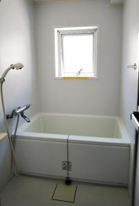 a white bath tub in a bathroom with a window at Hostel Belle Via Tokyo in Tokyo