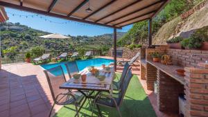 een patio met een tafel en stoelen en een zwembad bij Casa Amelia Competa by Ruralidays in Cómpeta