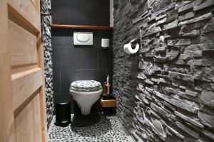 a bathroom with a white toilet and a brick wall at Les Posettes, appartement Le Sizeray - Mont Blanc in Vallorcine