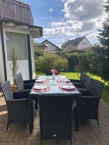 an outdoor table with chairs and plates and flowers on it at Ferienwohnung Eifel-Roedis in Blankenheim