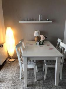 a white table and chairs with a lamp and flowers on it at Ferienwohnung Eifel-Roedis in Blankenheim