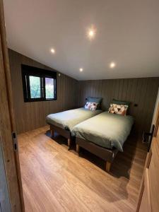 Saint-Sauveur-lès-BrayにあるChalet moderne au bord d'un lacのウッドフロアのベッドルーム1室(ベッド2台付)