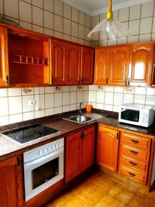 eine Küche mit Holzschränken, einer Spüle und einer Mikrowelle in der Unterkunft HERVEME AGAETE in Agaete
