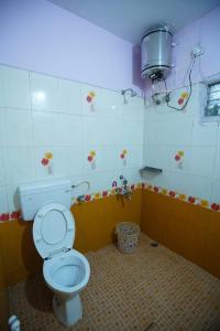 a bathroom with a toilet and a bucket on the wall at Vpr residency ooty in Ooty