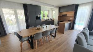 Il comprend une cuisine et une salle à manger avec une table et des chaises en bois. dans l'établissement Velence Lakeside Pool House, à Velence