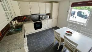a kitchen with white cabinets and a table with chairs at EG Apartment in Leknes