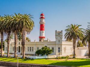 a lighthouse on top of a building with palm trees at Japie's Yard Wanderer's Inn in Swakopmund