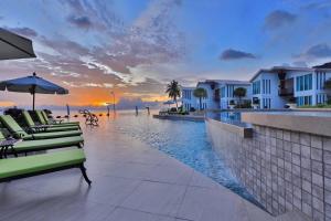 a resort with a pool and chairs and a sunset at Vannee Golden Sands Beachfront Resort in Haad Rin
