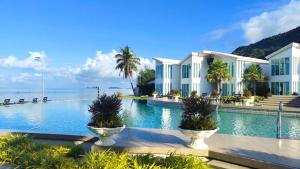 a swimming pool in front of a house with the ocean at Vannee Golden Sands Beachfront Resort in Haad Rin