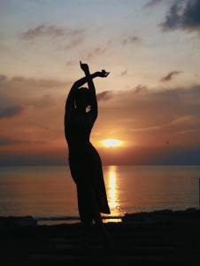 a woman dancing on the beach at sunset at Vannee Golden Sands Beachfront Resort in Haad Rin