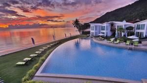 a resort swimming pool with a sunset in the background at Vannee Golden Sands Beachfront Resort in Haad Rin