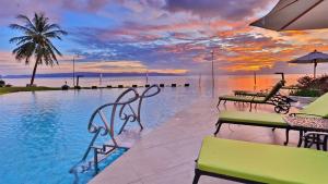 a pool with tables and chairs and a sunset at Vannee Golden Sands Beachfront Resort in Haad Rin