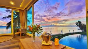 a room with a large window with a view of the ocean at Vannee Golden Sands Beachfront Resort in Haad Rin