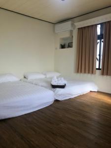 2 letti in una camera con lenzuola bianche di Starry Sky Hostel a Checheng Altre 3 foto