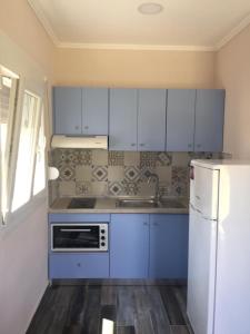 a kitchen with blue cabinets and a white refrigerator at NA House 2 in Nea Kalikratia