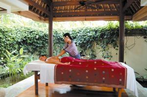 a woman giving a man a massage on a bed at The Oberoi Beach Resort, Lombok in Tanjung