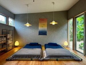 a bedroom with a large bed in a room with windows at Green Rabbit Studio in Ishigaki Island