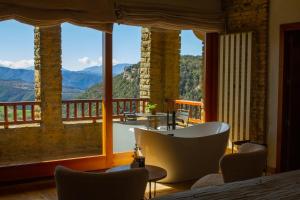 a room with a tub and a balcony with mountains at Masia Santa Llúcia in Rupit