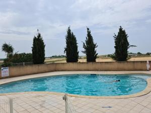 een persoon die zwemt in een zwembad met bomen op de achtergrond bij Villa 6 personnes dans résidence avec piscine in Portiragnes