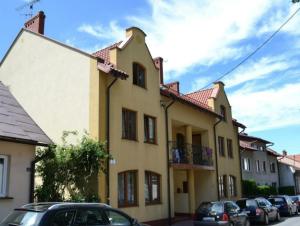 a yellow building with cars parked in front of it at Apartament przy Walowej in Łańcut