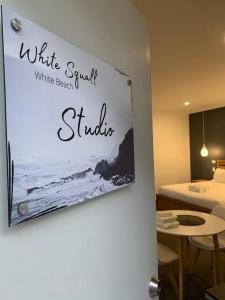 a sign for a white room with a bed and a table at Beachfront self contained studio in White Beach
