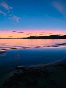 un coucher de soleil sur une étendue d'eau avec dans l'établissement Beachfront self contained studio, à White Beach