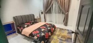a bedroom with a bed and a chair and a window at Aaira Sophea Islamic Homestay in Batu Pahat