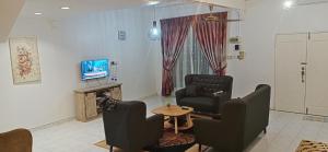 sala de estar con 2 sillas, mesa y TV en Aaira Sophea Islamic Homestay en Batu Pahat