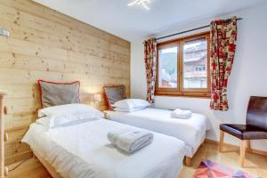 two beds in a room with a chair and a window at Le Slalom - Very Town Centre - Snow and Trek in Morzine